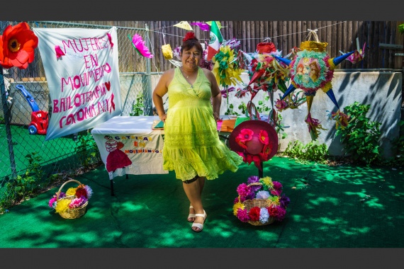 A woman standing in front of a table with piñatas nearby