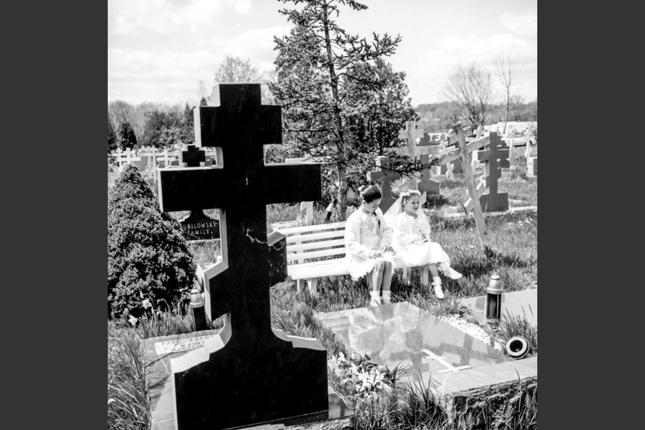 Two girls on a bench in a cemetery.