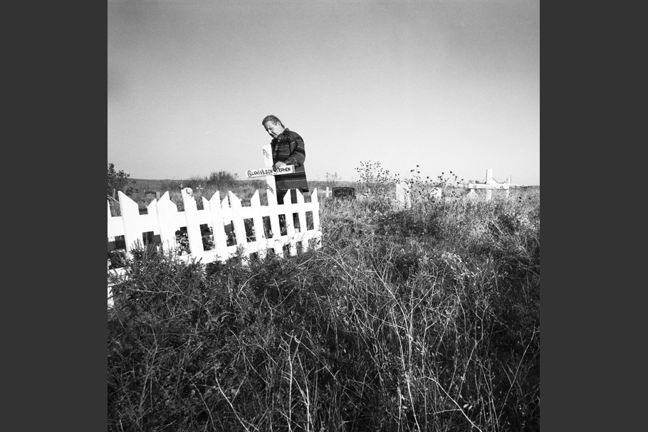 A man stands at a fenced grave.
