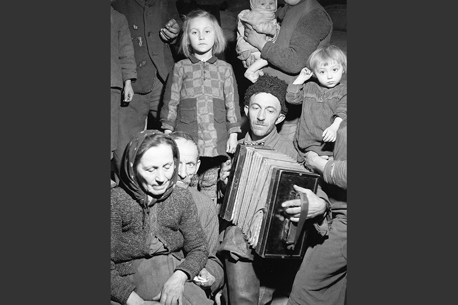 A group of people surrounding a man with an accordion.