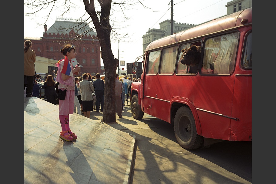 A girl looks at a bear in a bus.