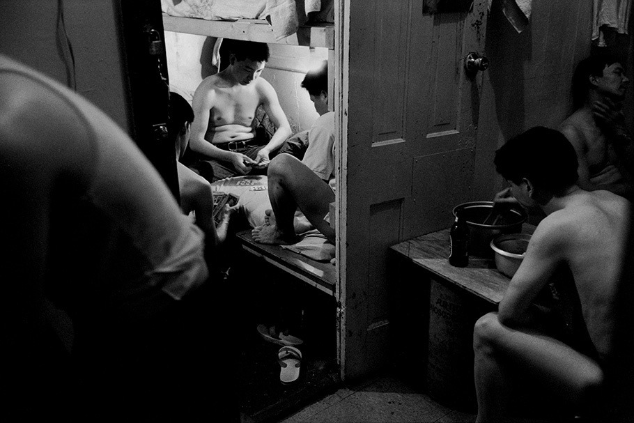 Men playing cards in a small space. 