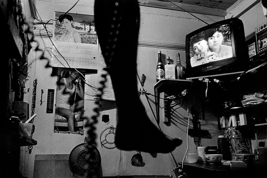 A foot dangling with a TV in the background.