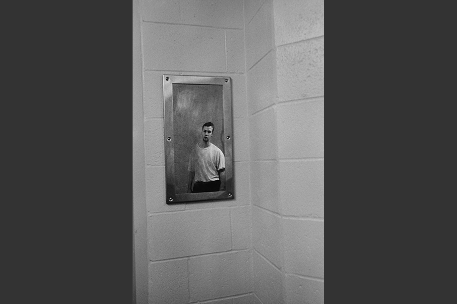 A teenage boy reflected in a cell mirror.
