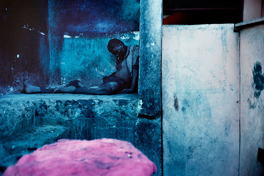 A man slumped in a corner with pink in the foreground.
