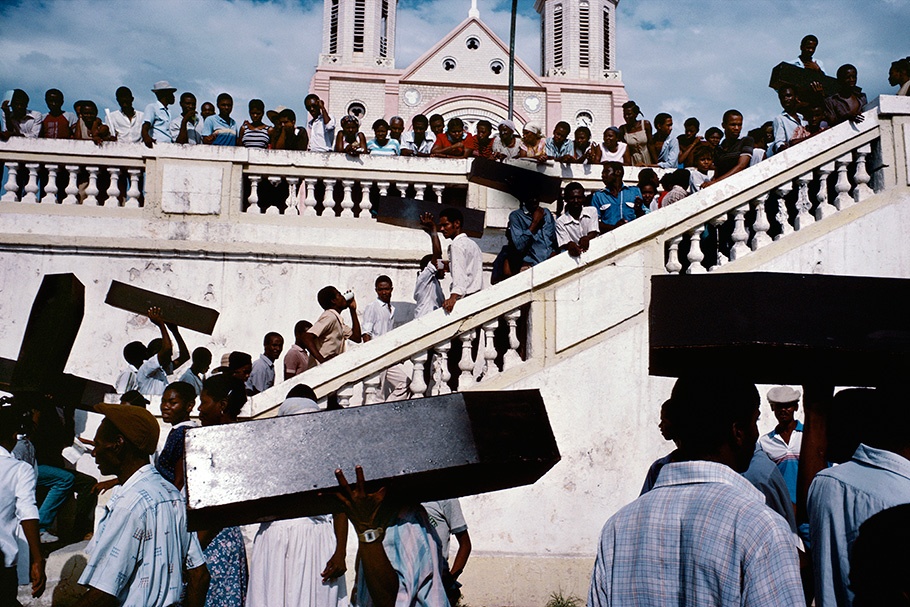 A crowd with coffins in front of a church.