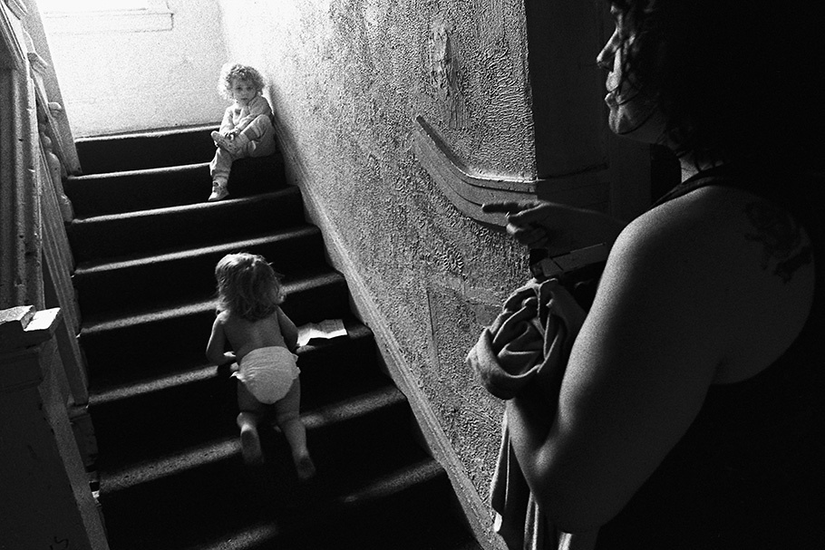 A women watching two children on a staircase.