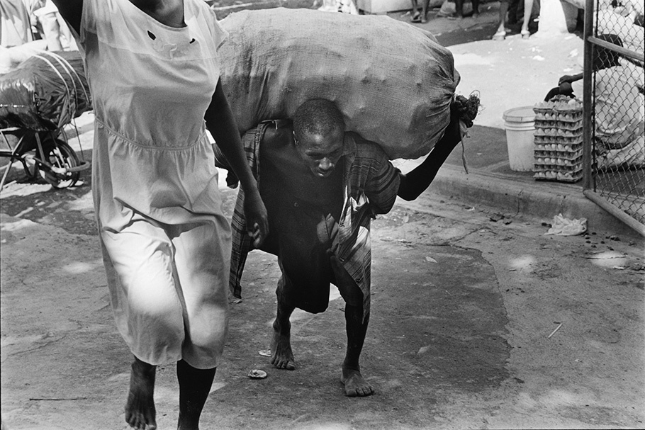 A man carrying a heavy sack on his back.