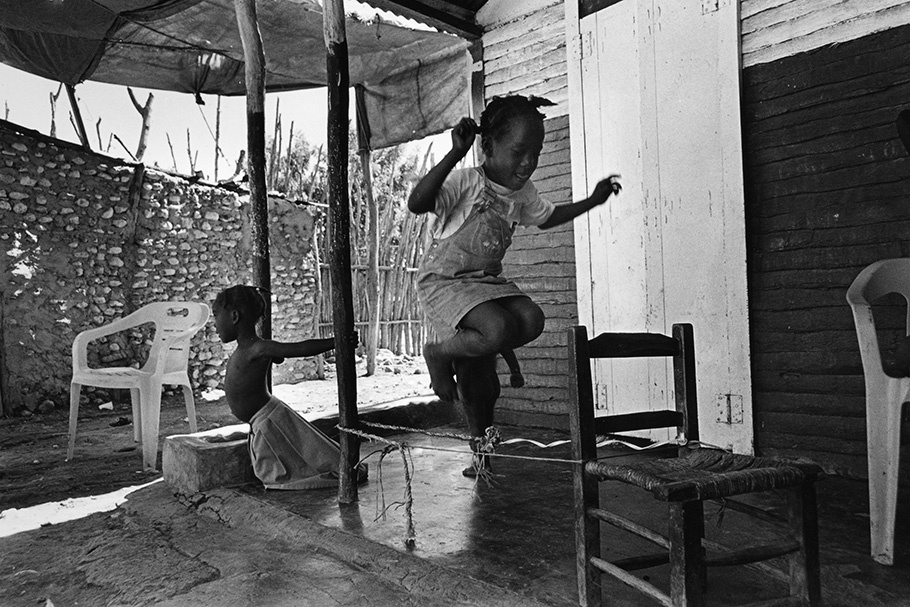 Children jumping rope on a porch.