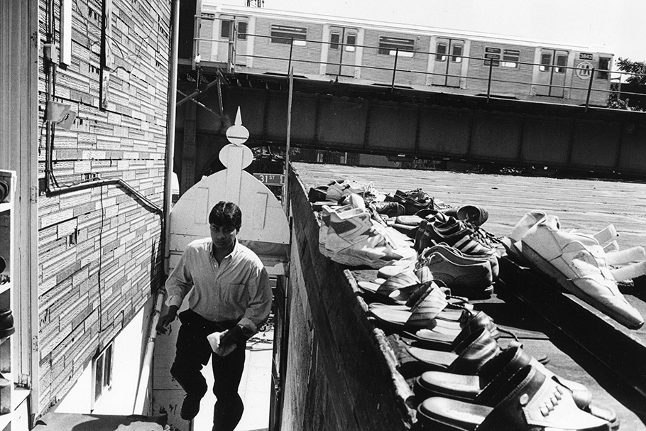 A man with a row of shoes and a subway train. 