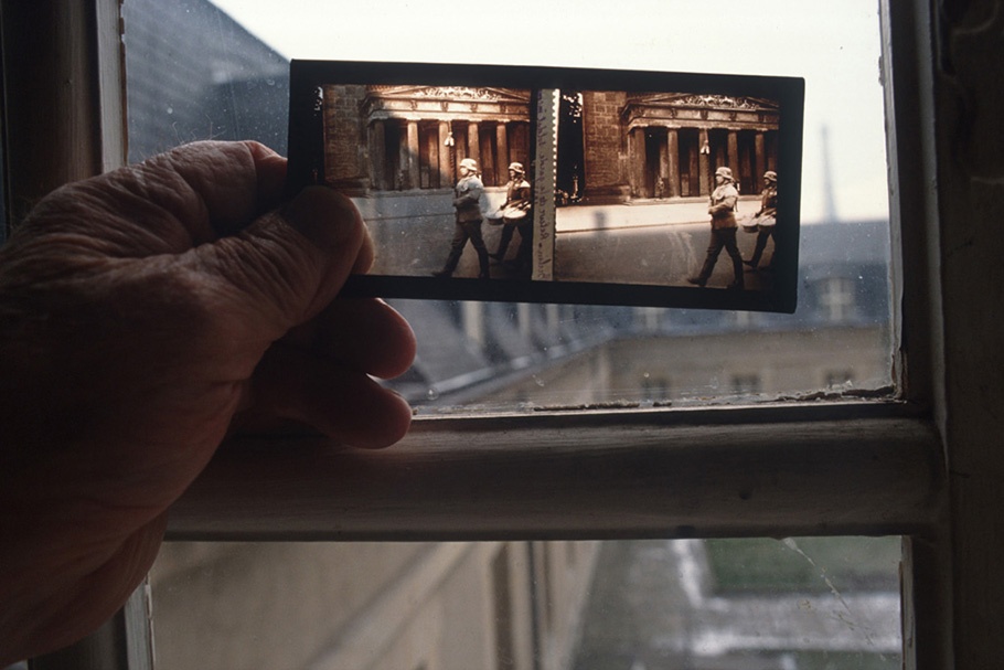 A hand holding color film in front of a window.