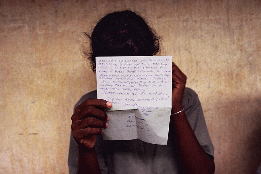 A girl holds a letter in front of her face.