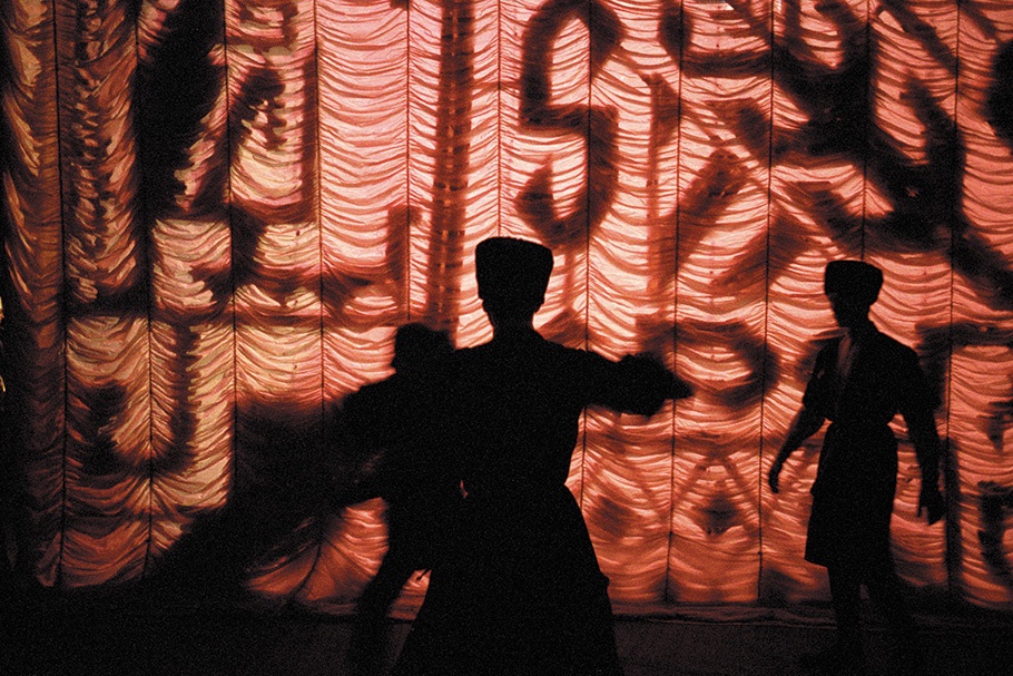 Performers in front of a red illuminated backdrop.