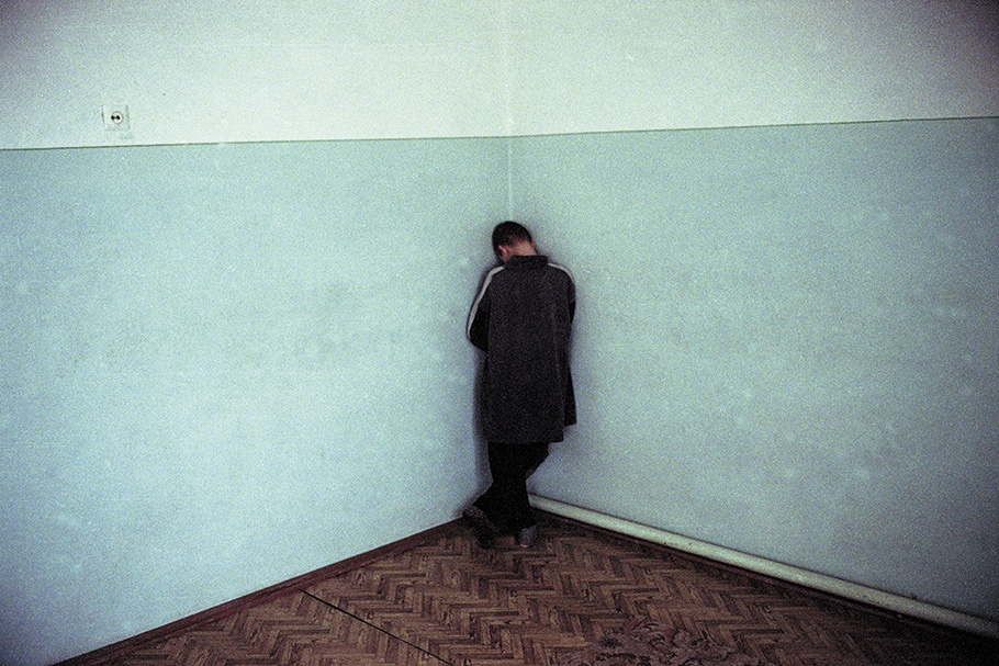 A child facing the corner of a room.