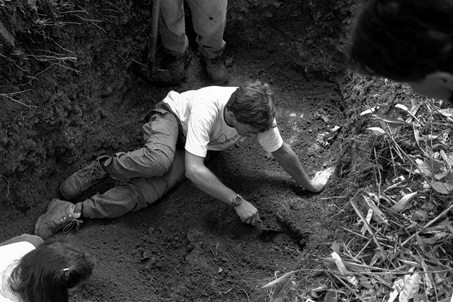 Man seated in dirt, digging.