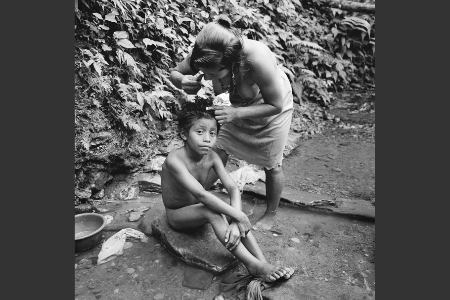 A mother checking her son’s hair for lice.