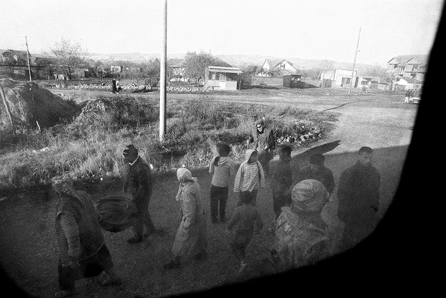 A group of people viewed from a train window.