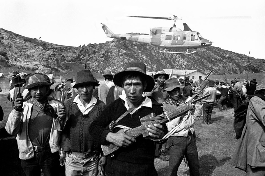 Armed men in front of a helicopter.