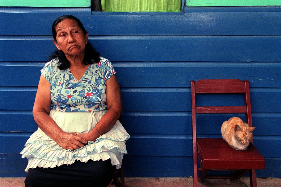 A woman and a cat seated in front of a blue wall.