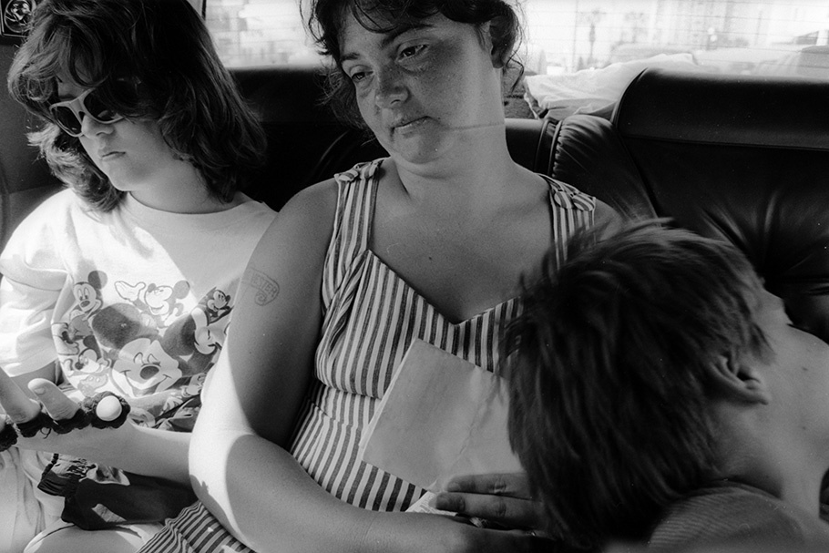 A woman and two children in the backseat of a car.