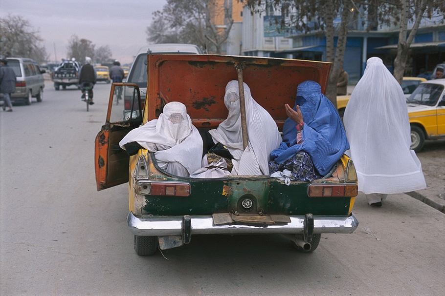 Women in burqas sitting in the trunk of a car.