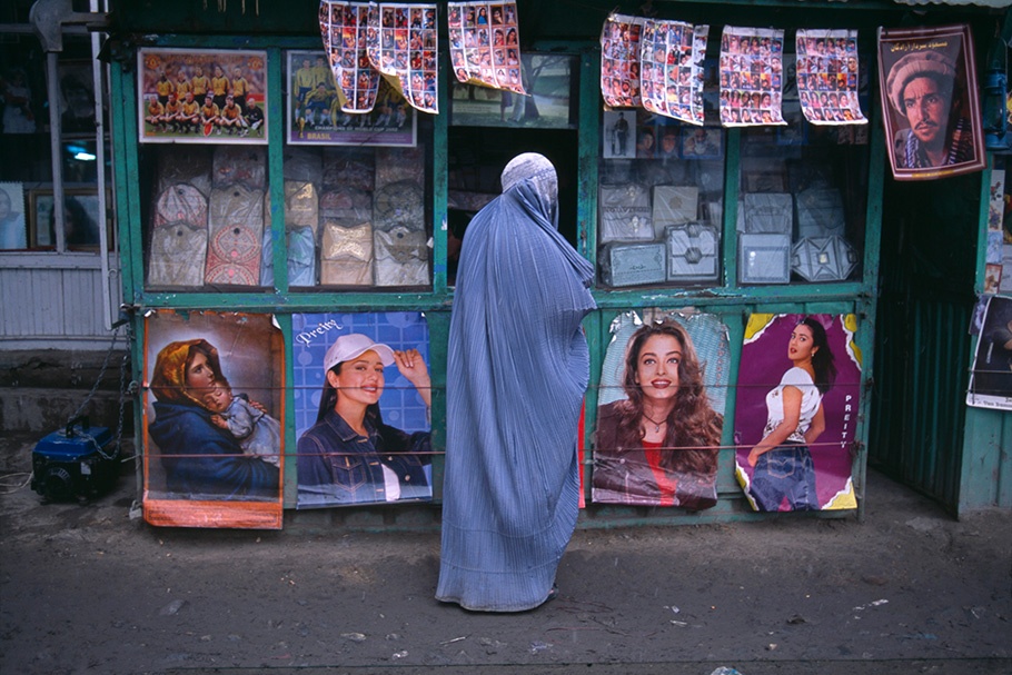 A woman in a burqa in front of movie posters.