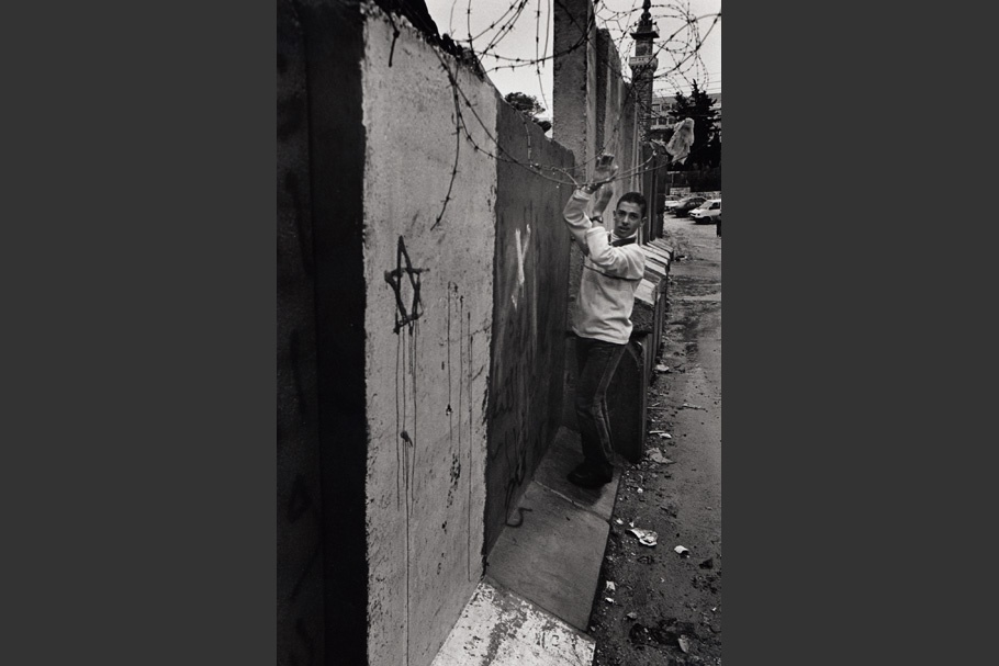 A boy walks along the wall with a painted Star of David.