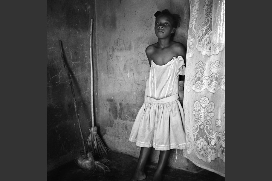 Girl posing in white dress next to brooms.