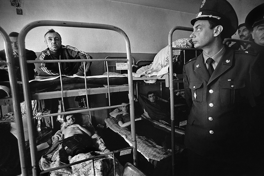 A guard with prisoners on bunk beds.