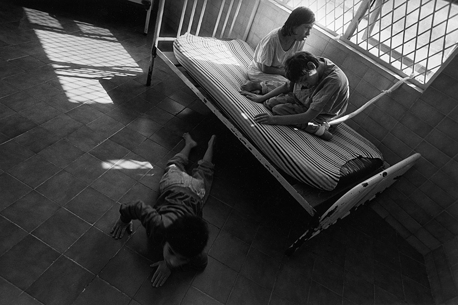 Two children on a bed and one on the floor.