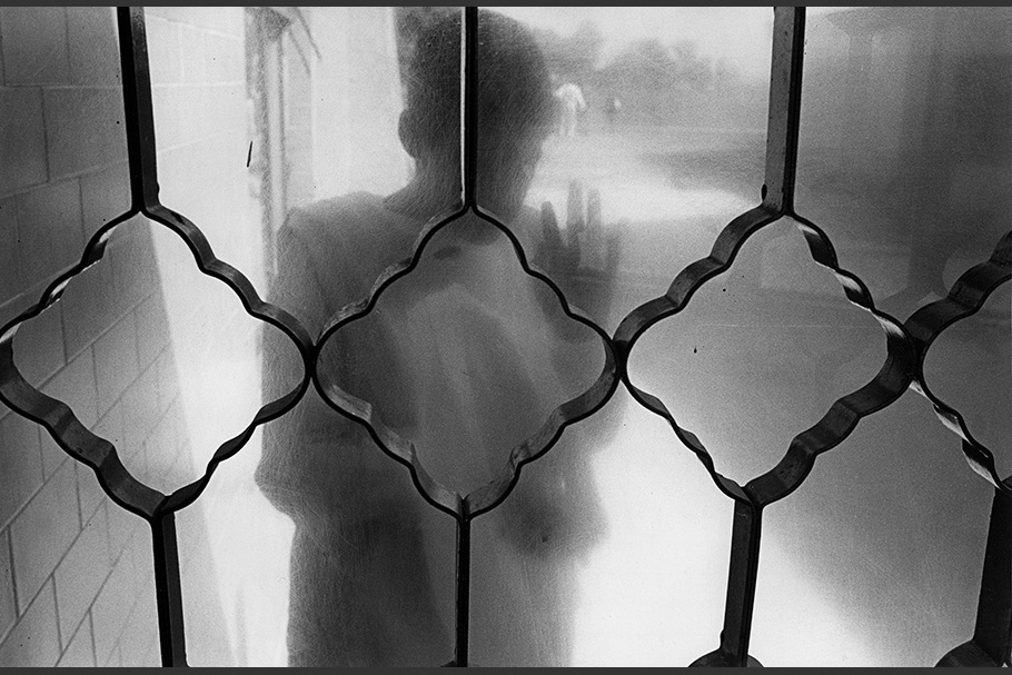 A patient viewed through frosted glass and patterned bars.