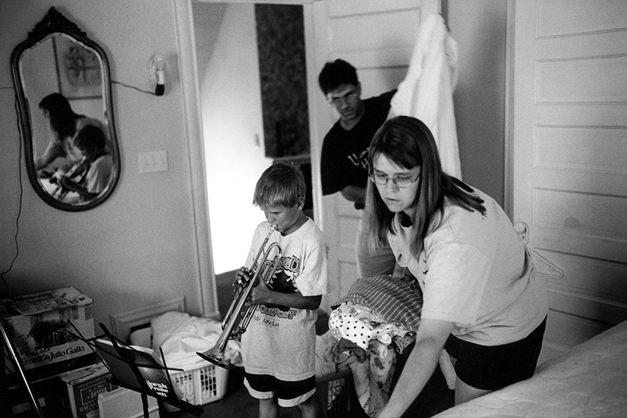 Parents folding laundry and a boy playing trombone.