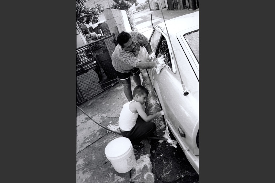 A father and son wash a car together.