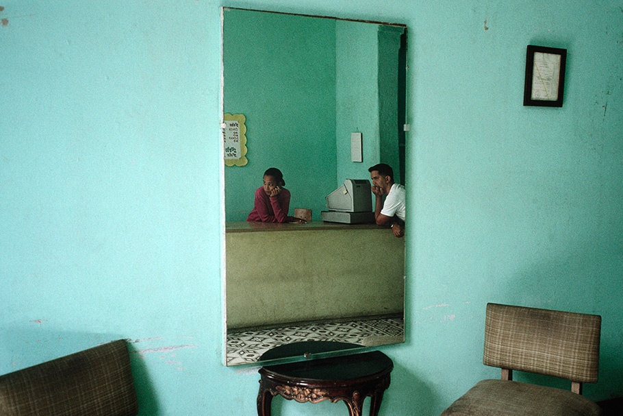 Man and woman leaning on a counter reflected in a mirror.