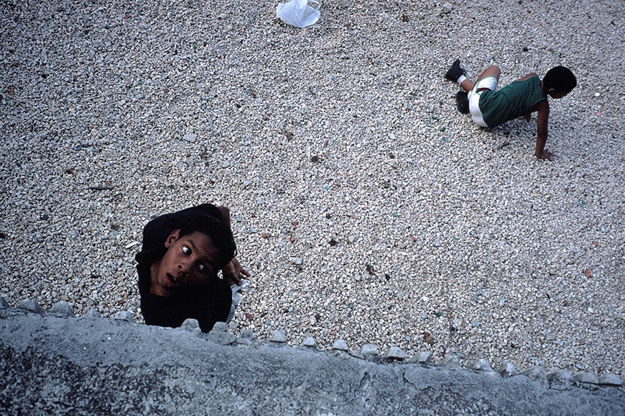 A boy looking through a hole and another on the ground.