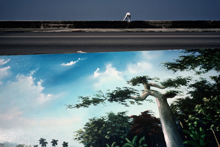 A person perched above a mural.