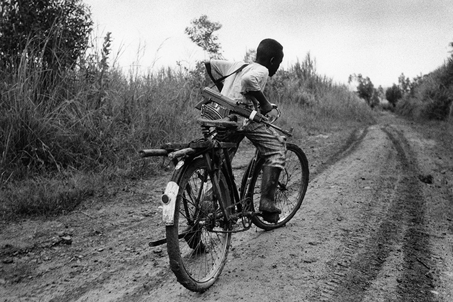 A child soldier on a bicycle.