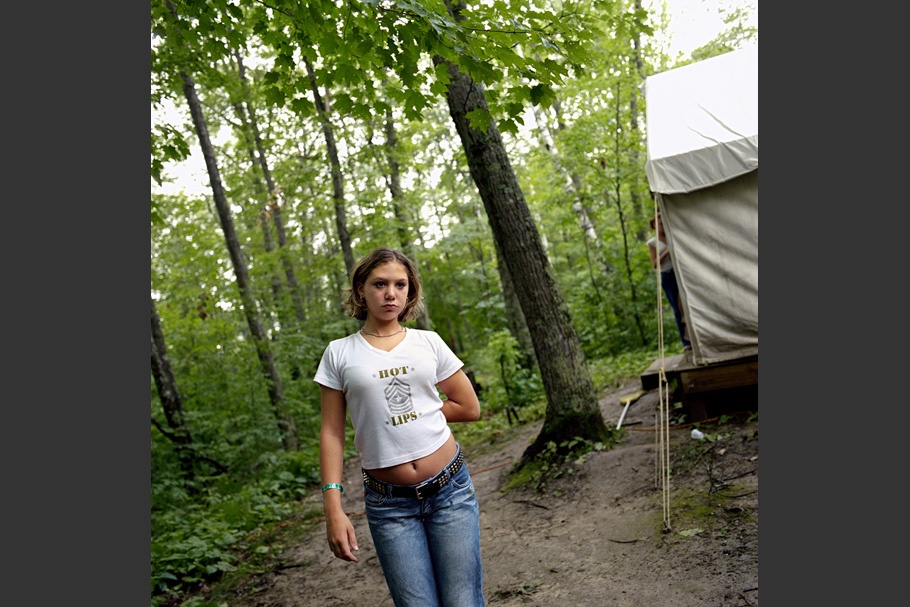 Teenage girl in jeans and a white t-shirt outside of a tent.