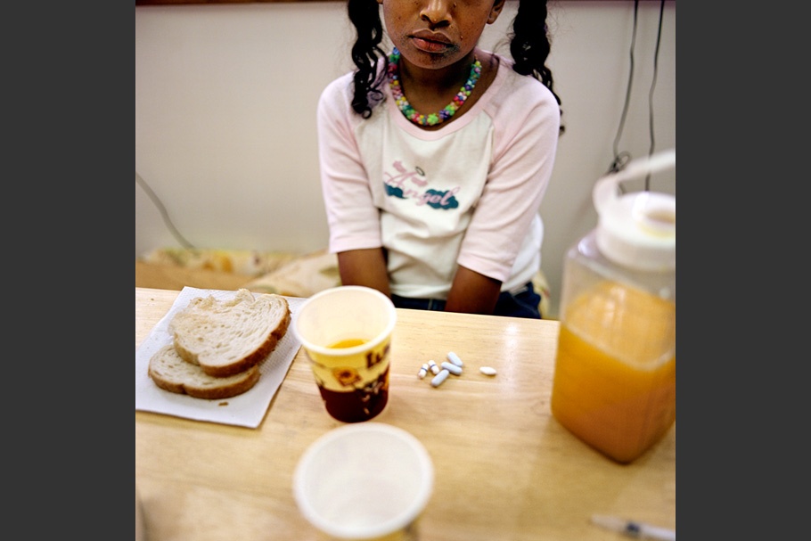 A child at a table with pills and food.