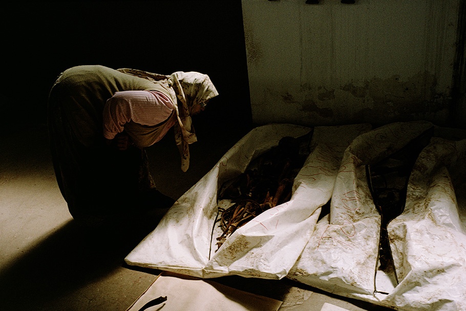 Women looking at remains in body bags.