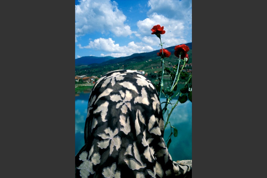 A woman in a headscarf viewed from behind, with flowers.