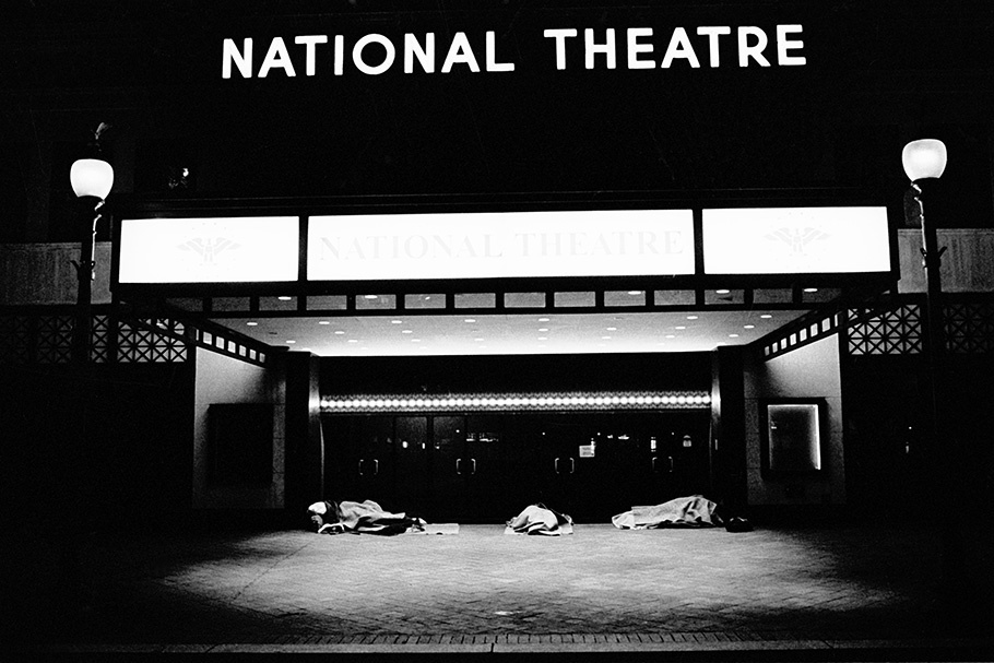 People sleeping under a theater marquee.