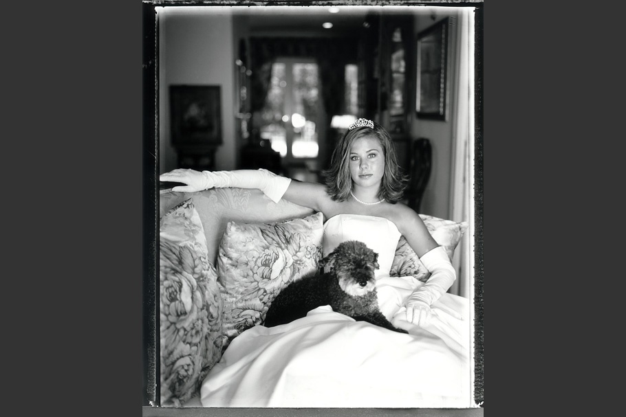Girl in debutante gown with a dog on her lap.