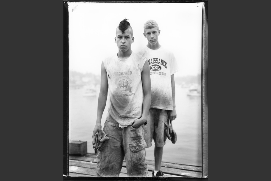 Two teenage boys standing on a dock, one with a mohawk.