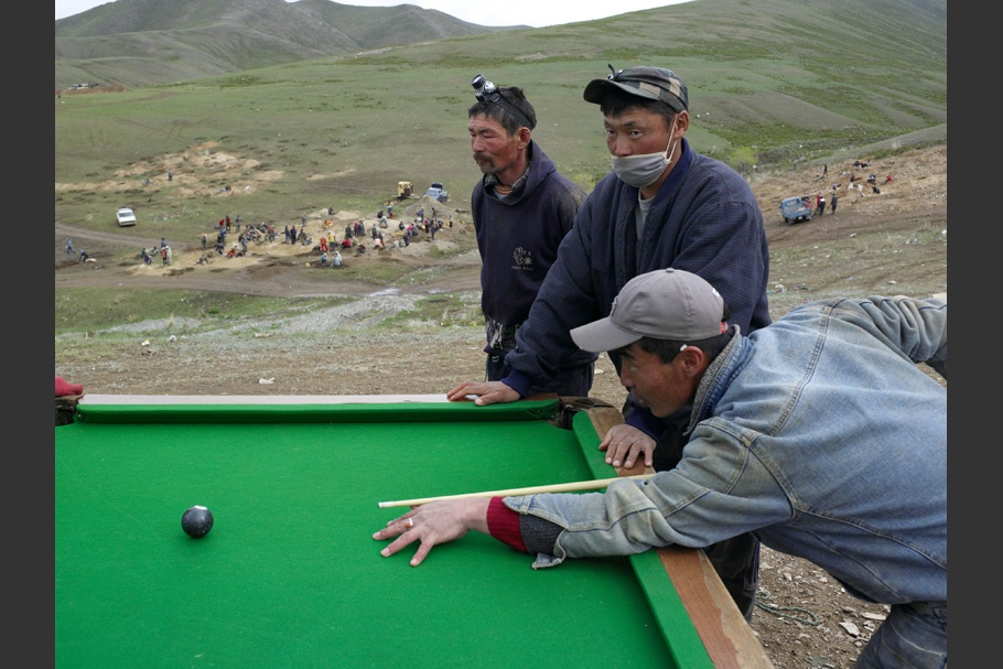 Men playing pool at an open air table.