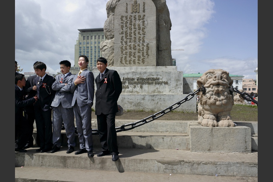 Boys in suits in front of a statue.