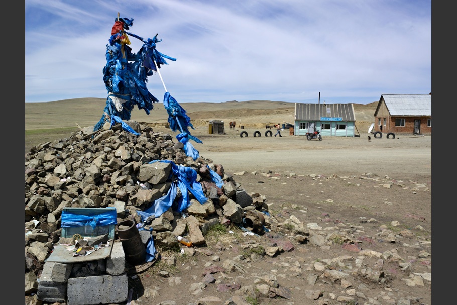 Tangle of blue prayer flags on top of a stone cairn. 