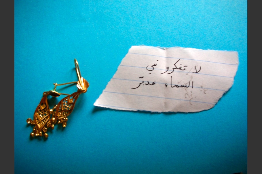 A pair of earrings a note against a blue background.