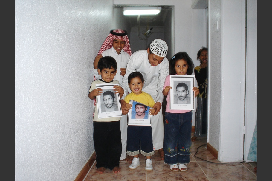 A family with children holding framed photographs.