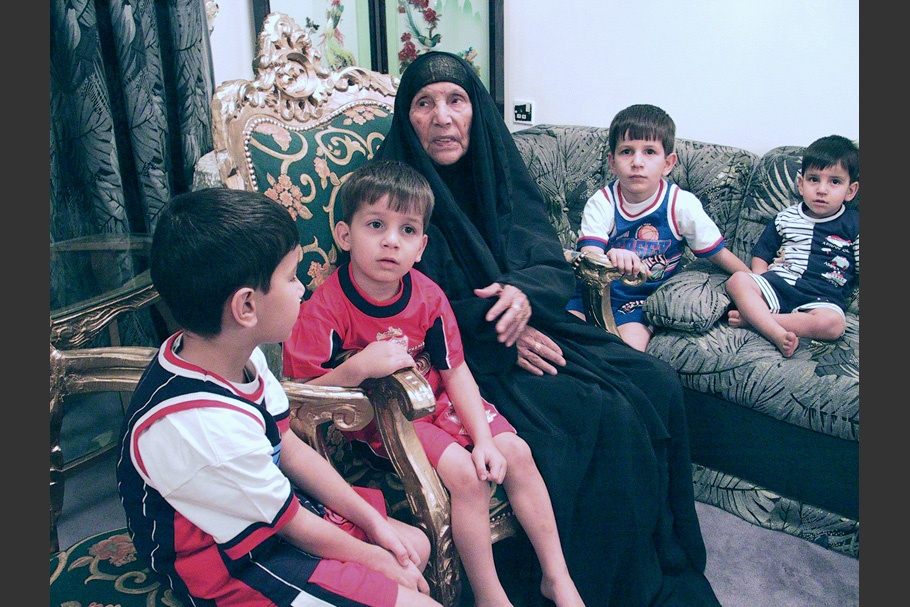 A woman wearing black with four boys.